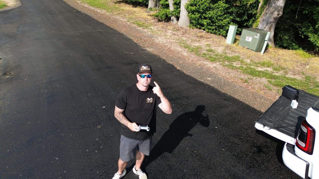 One Vision Roofing technician on site operating an inspection drone, photographed from the drone