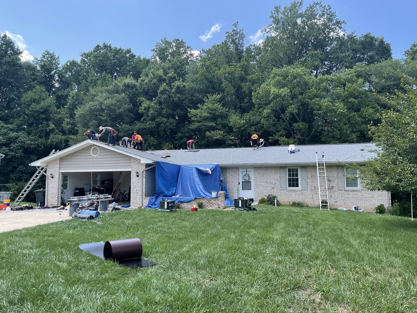 Roofing crew at work on a ranch home with tarps protecting the landscaping