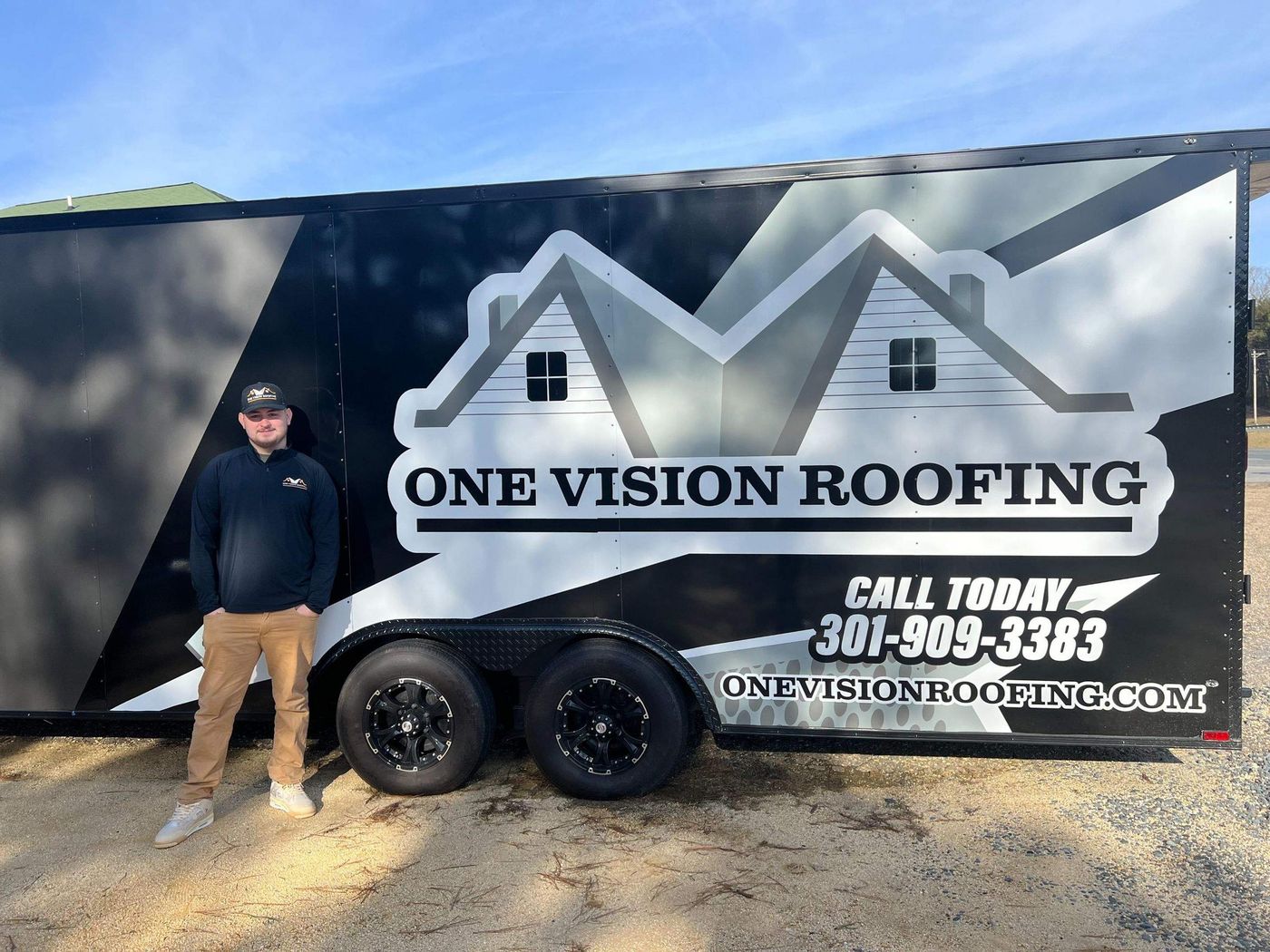 One Vision Roofing team member beside the company's branded trailer