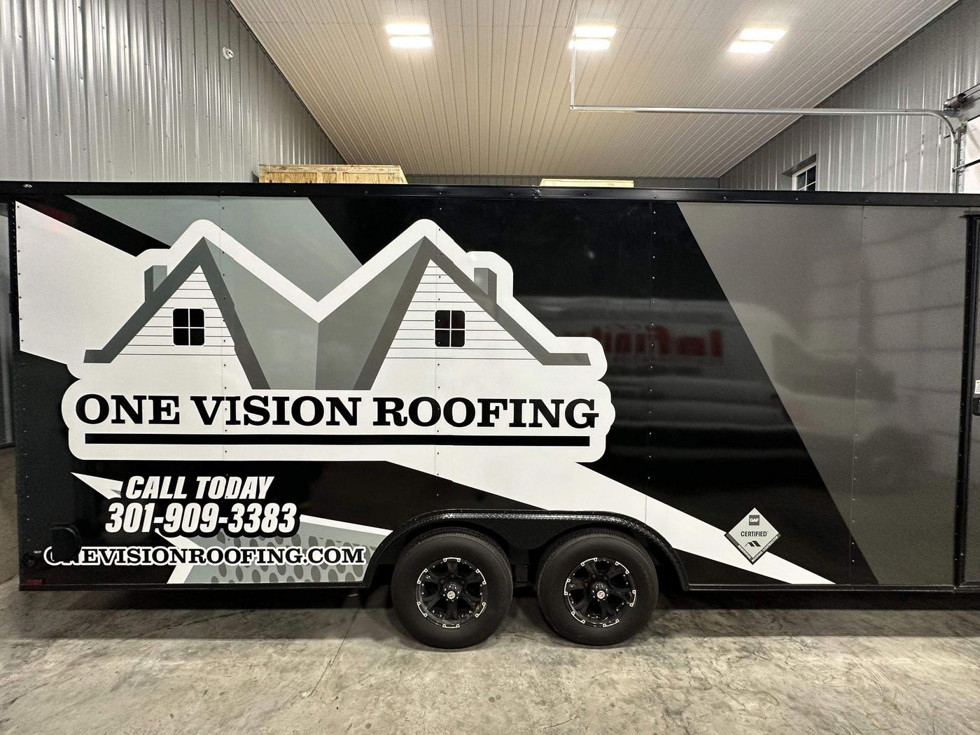 One Vision Roofing branded trailer parked indoors