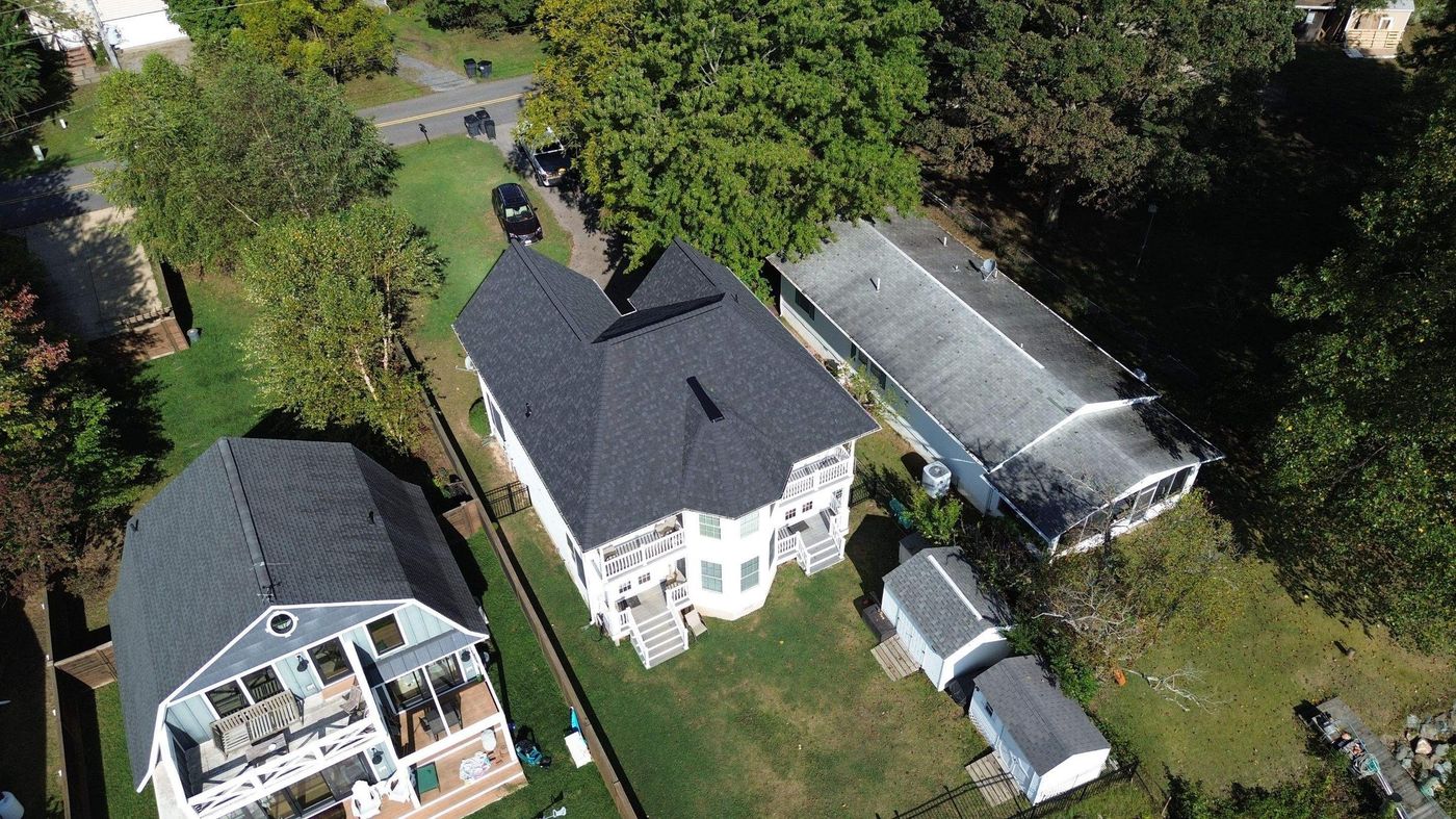 Aerial view of neighboring homes with shingle and low-slope roofs