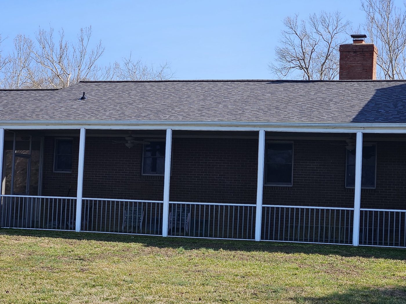 Low-slope roof over a long screened porch on a brick home