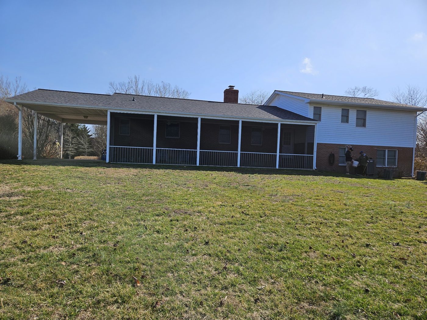 Brick and siding home with a carport and screened porch roof