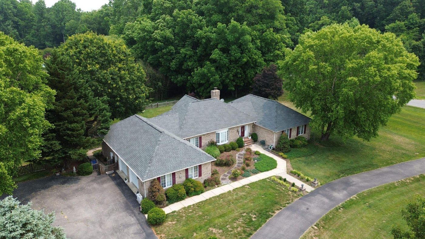 Aerial view of a large single-story home with a gray roof among trees
