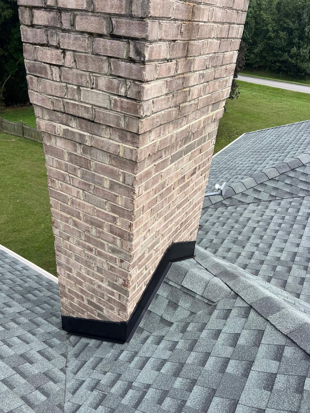 New shingles and flashing tied into a brick chimney
