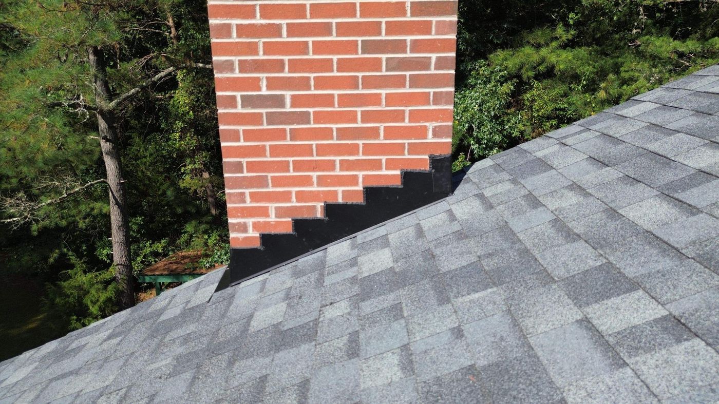 Step flashing where new shingles meet a brick chimney