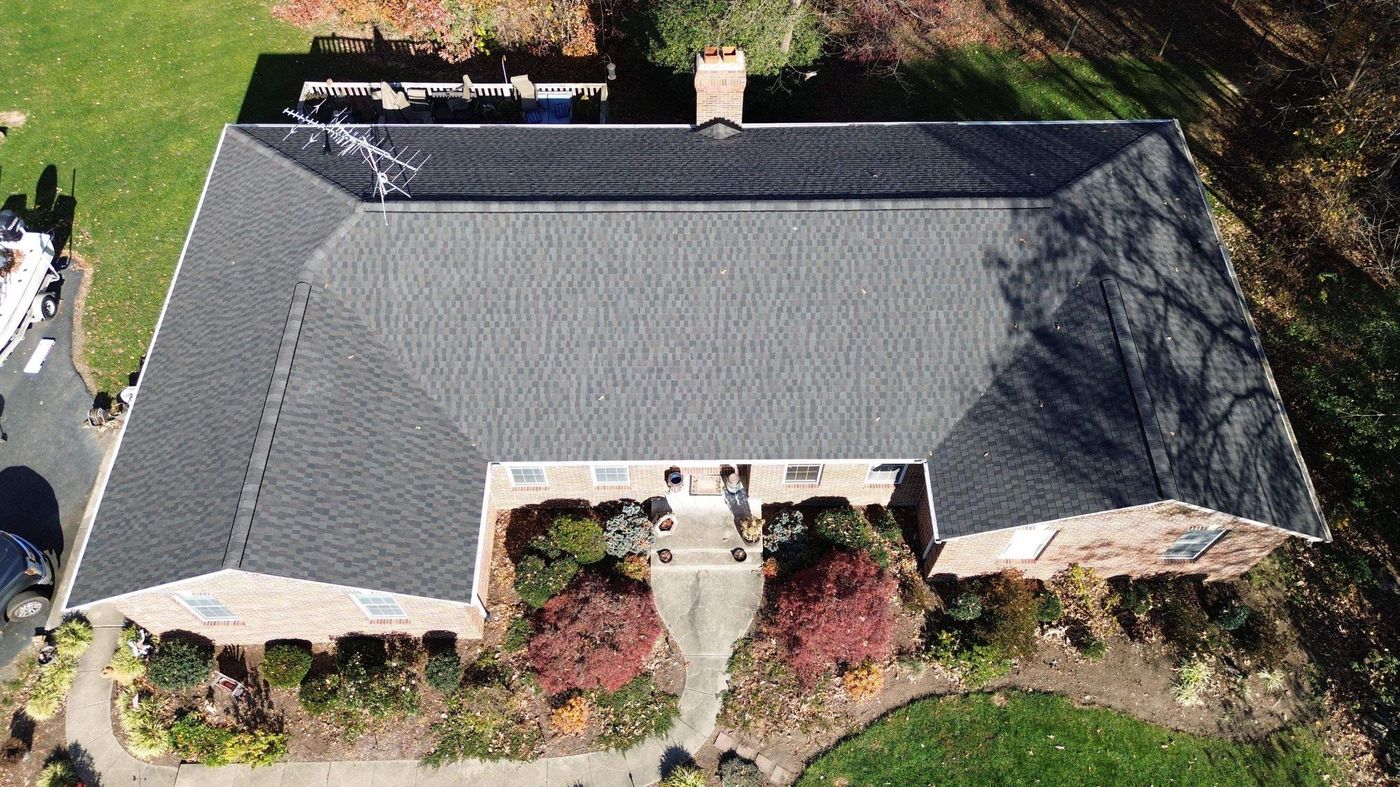 Aerial view of a hip roof with dark shingles on a brick home