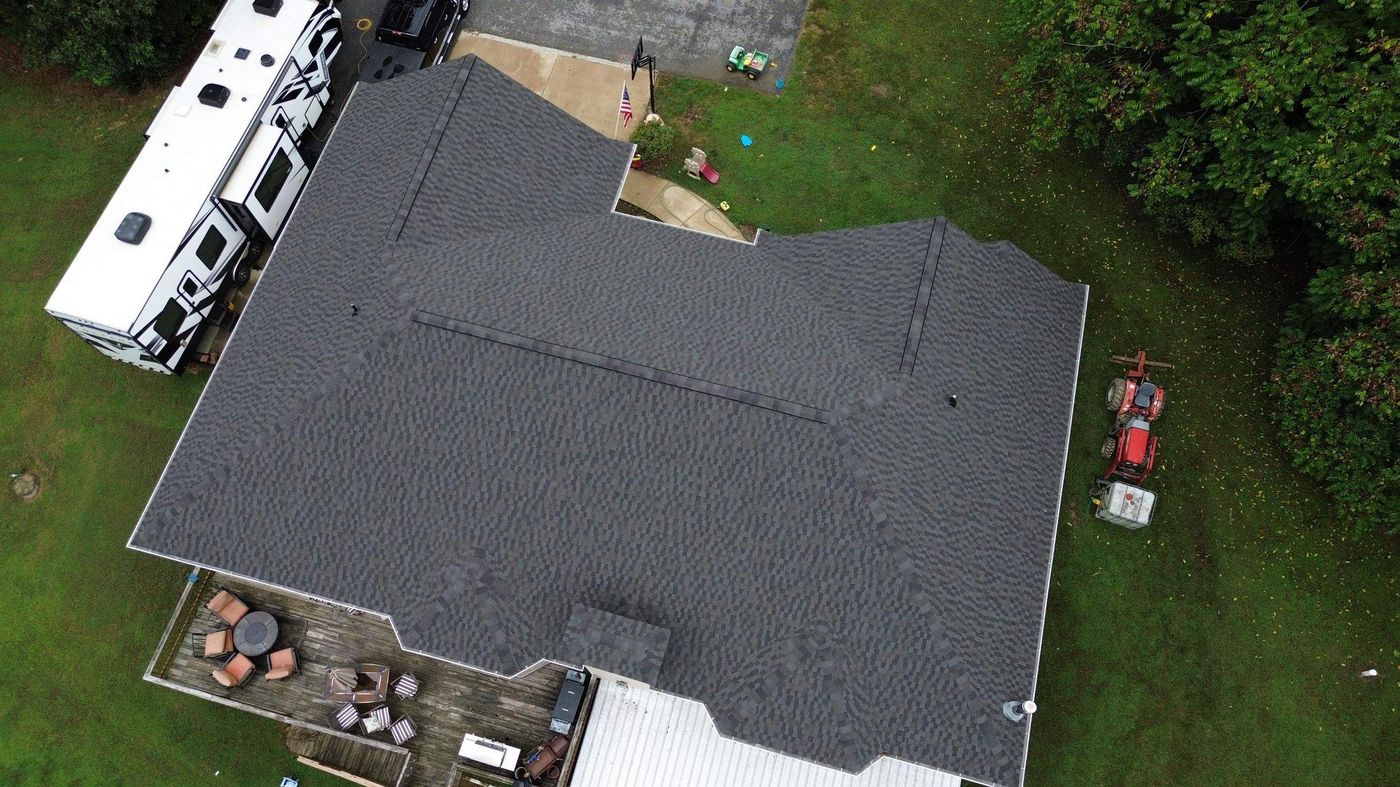 Aerial view of a dark shingle roof on a large home with an RV parked beside it