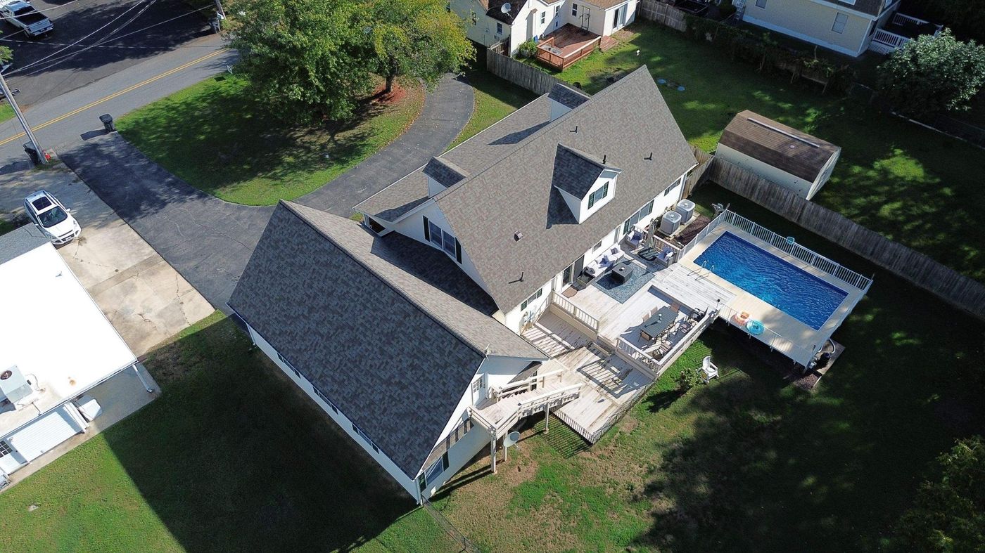 Aerial view of a charcoal shingle roof over a home with a backyard pool
