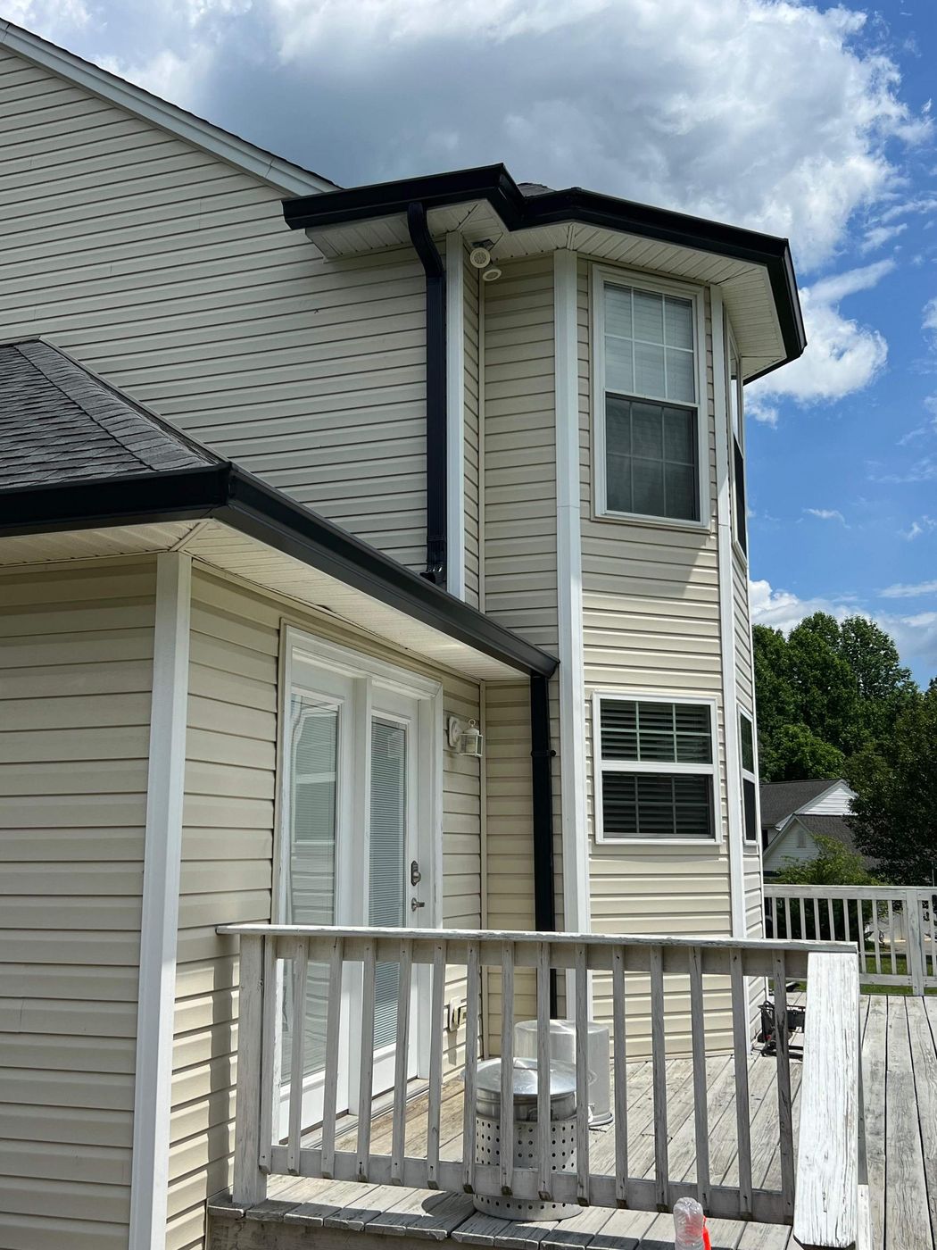 Two-story home with light siding and a white deck railing