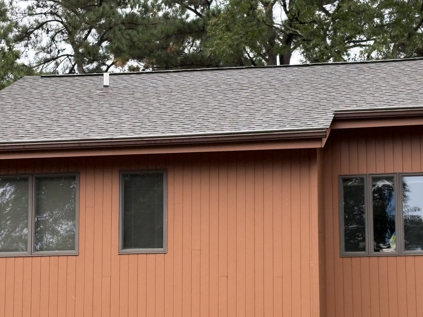Brown vertical siding under a dark shingle roofline