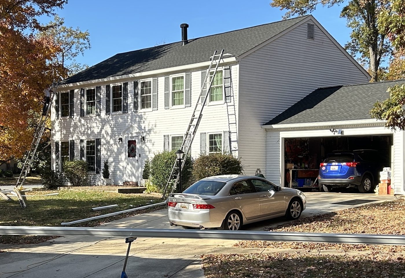 Two-story colonial home with ladders set up for trim and gutter work